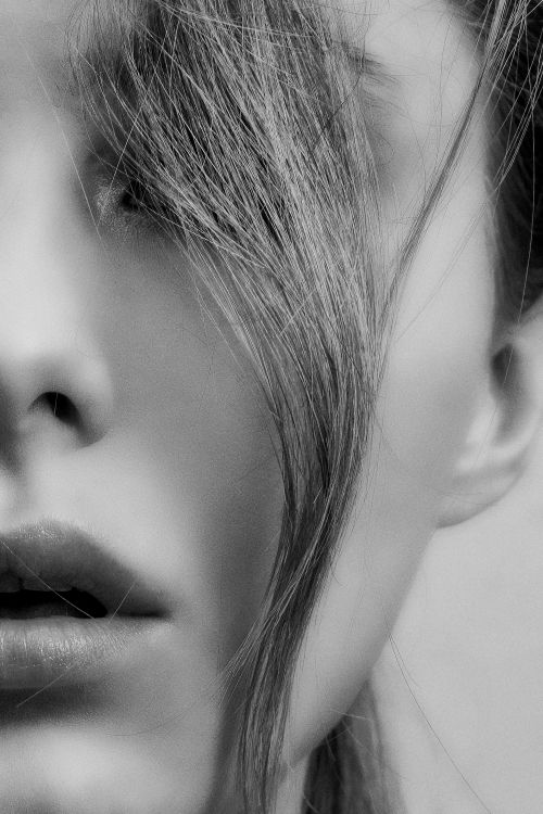 Free Close-up black and white portrait of a woman with hair falling across her face, showcasing elegance and mystery. Stock Photo