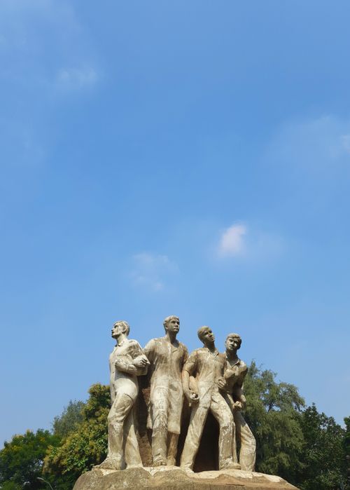 Free Statue of four figures under a clear blue sky, Dhaka, Bangladesh. Stock Photo