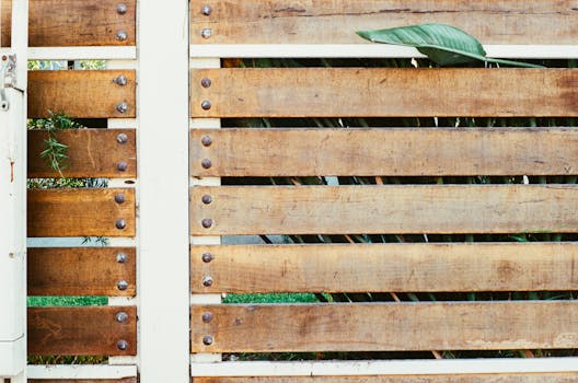 Close-up of a rustic wooden fence with green leaves peeking through the gaps.