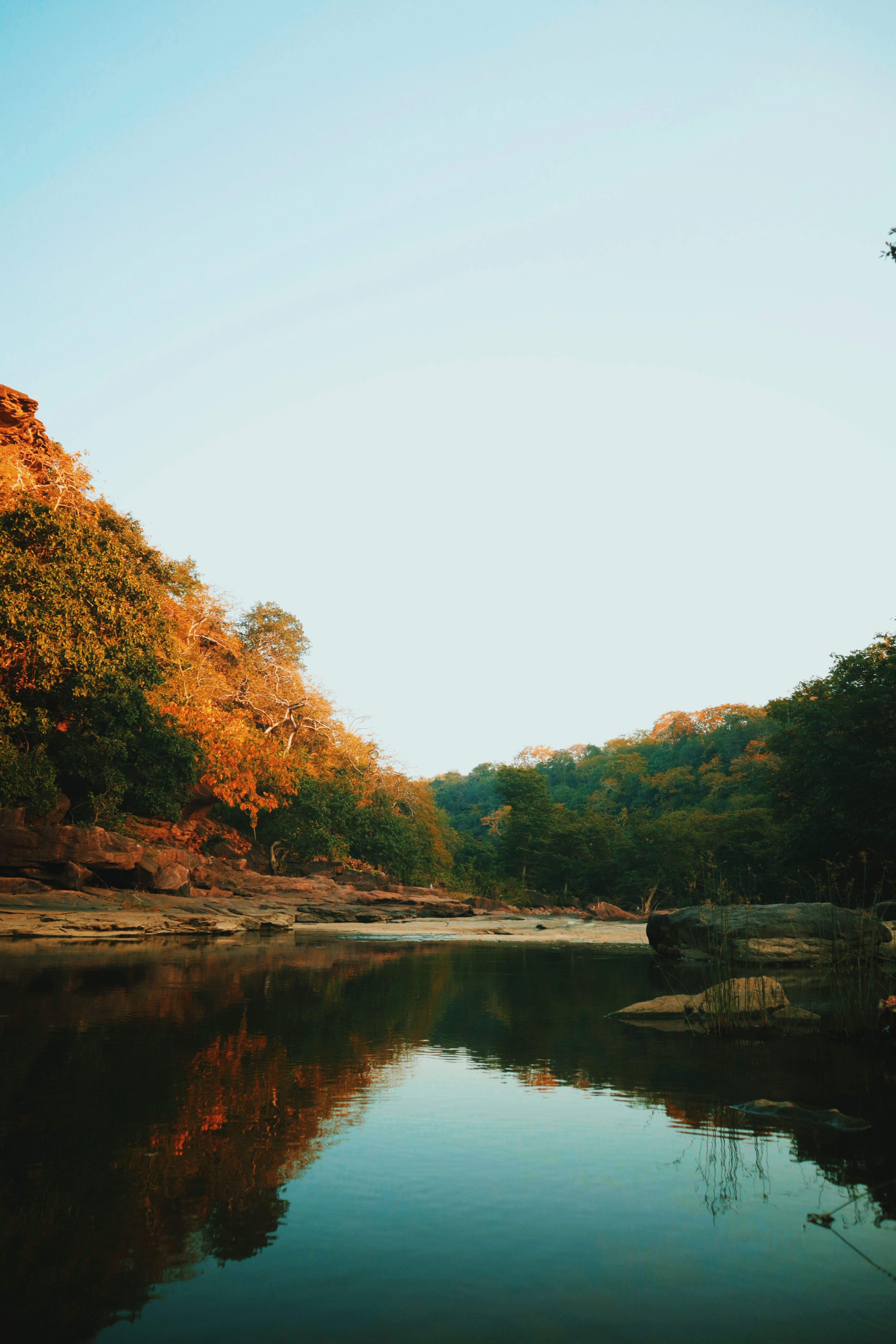 Beautiful autumn landscape of a tranquil river surrounded by vibrant foliage reflected in water.