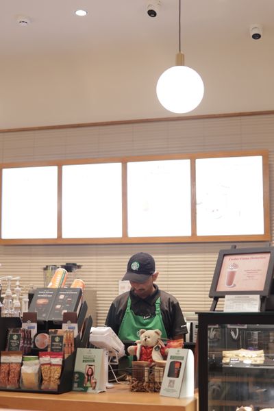 A barista in a green apron working at the counter of a cosy coffee shop