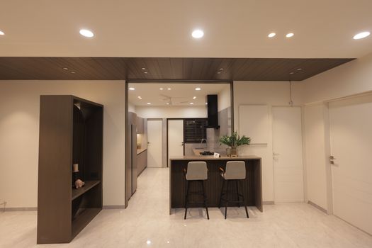 A sleek and modern kitchen interior featuring minimalist design with bar stools and functional layout.