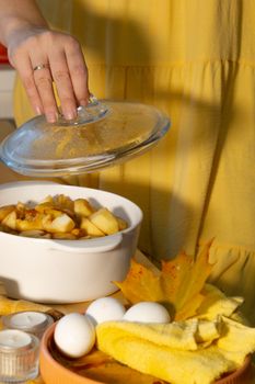 Woman in yellow dress preparing apple pie with autumn theme.