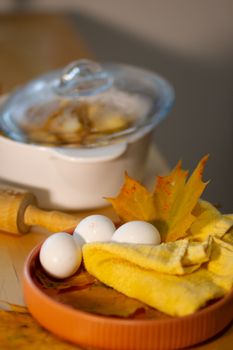 Cozy autumn kitchen setup with eggs, maple leaf, and cookware.