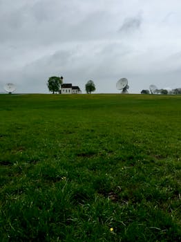 阴天里，风景优美的乡村景观中，有一座孤独的房子，屋顶上装着卫星天线