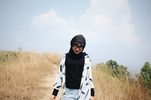 Photo of Woman in Black Hijab Walking Alone on Dirt Road