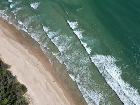 A stunning aerial shot capturing waves and sandy shores at a Queensland beach in Australia.
