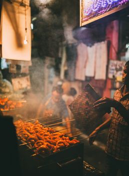 A street food vendor grills tasty snacks at a bustling night market in Delhi, India.