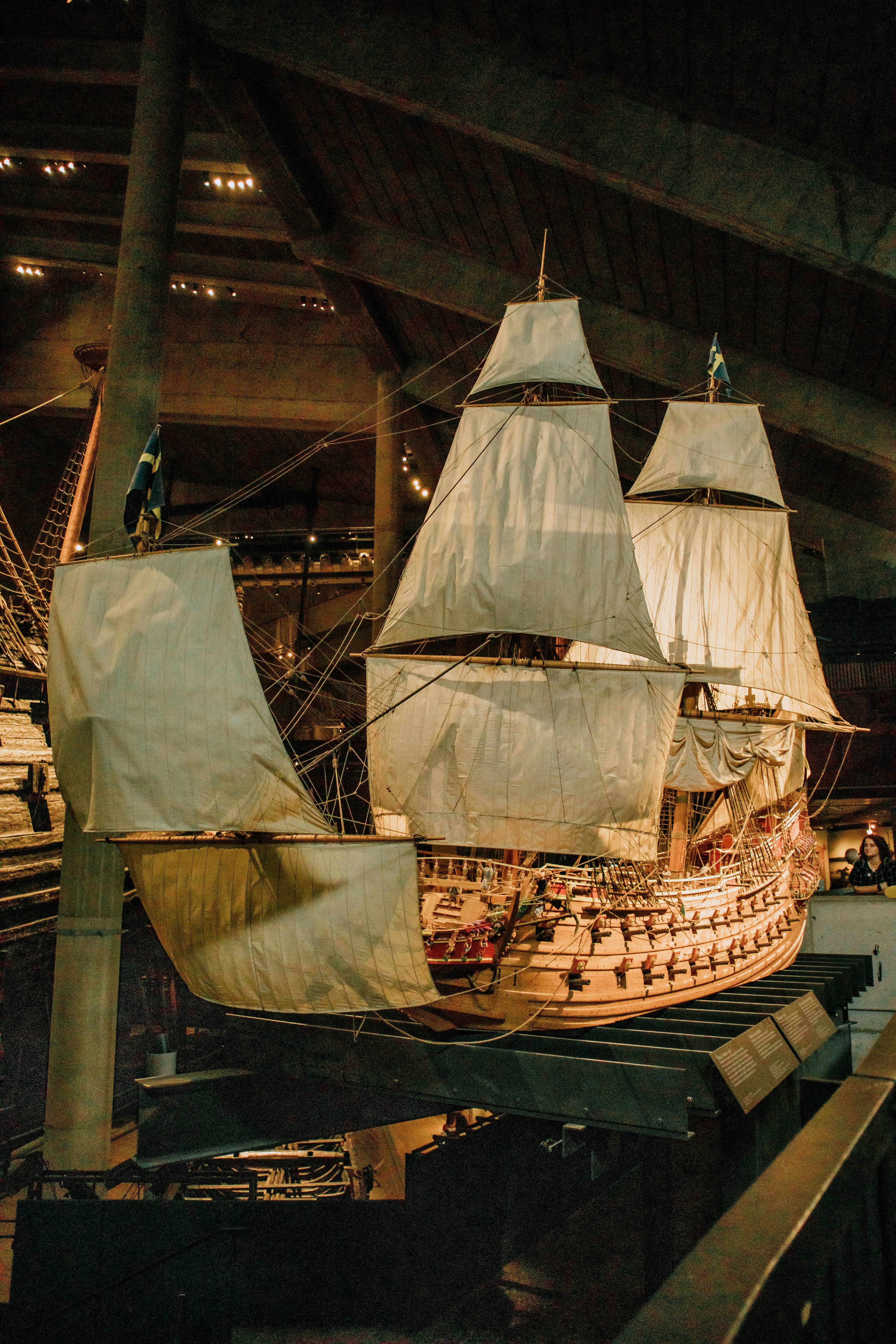 Large historic ship indoors at a maritime museum with dramatic lighting.
