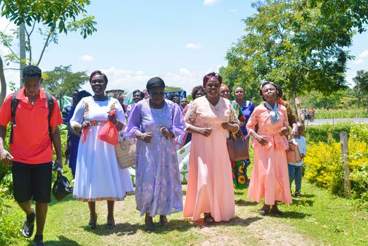 A joyful gathering of adults in colorful attire enjoying an outdoor celebration on a sunny day.