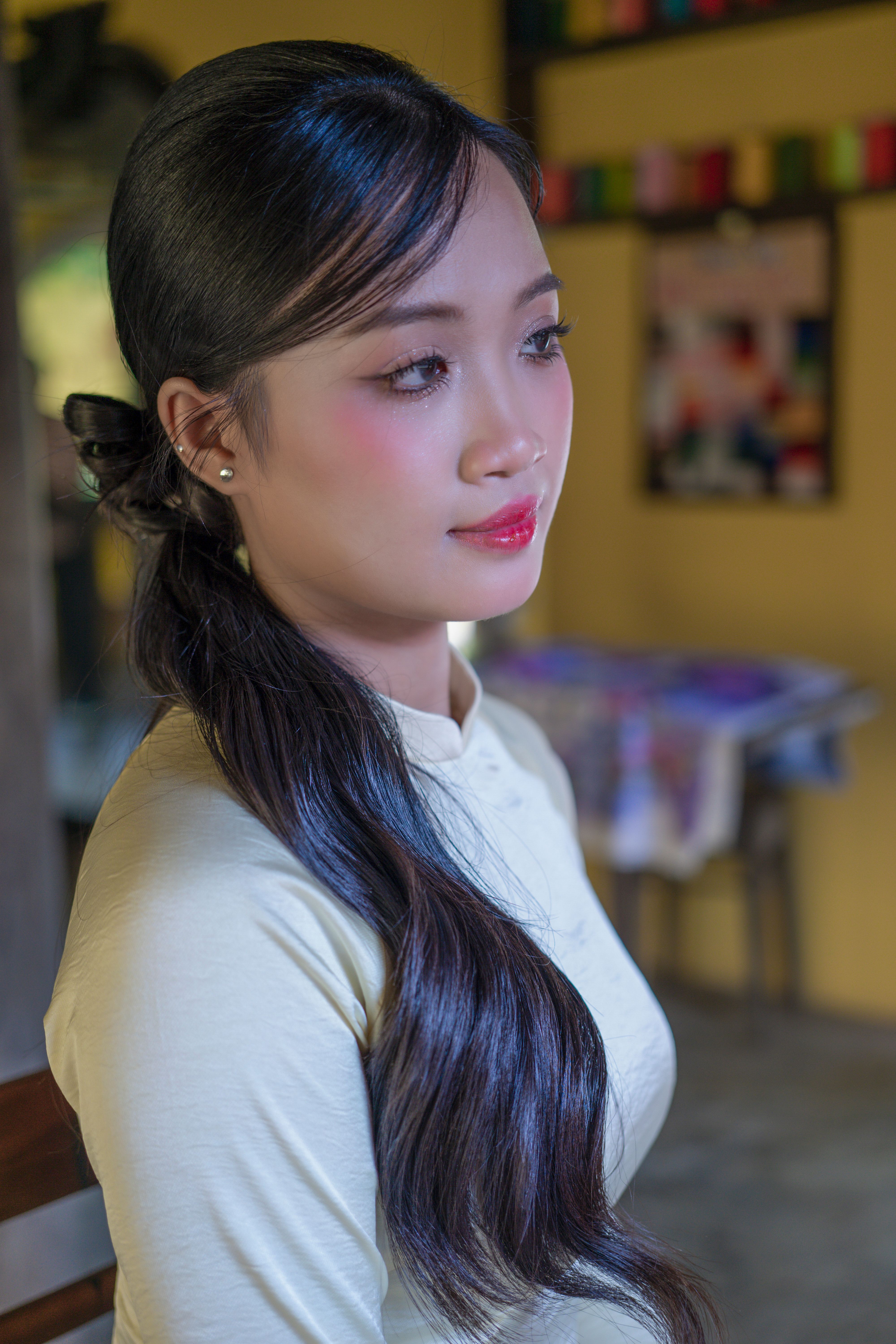 A serene portrait of a young woman with long hair in a softly lit room.
