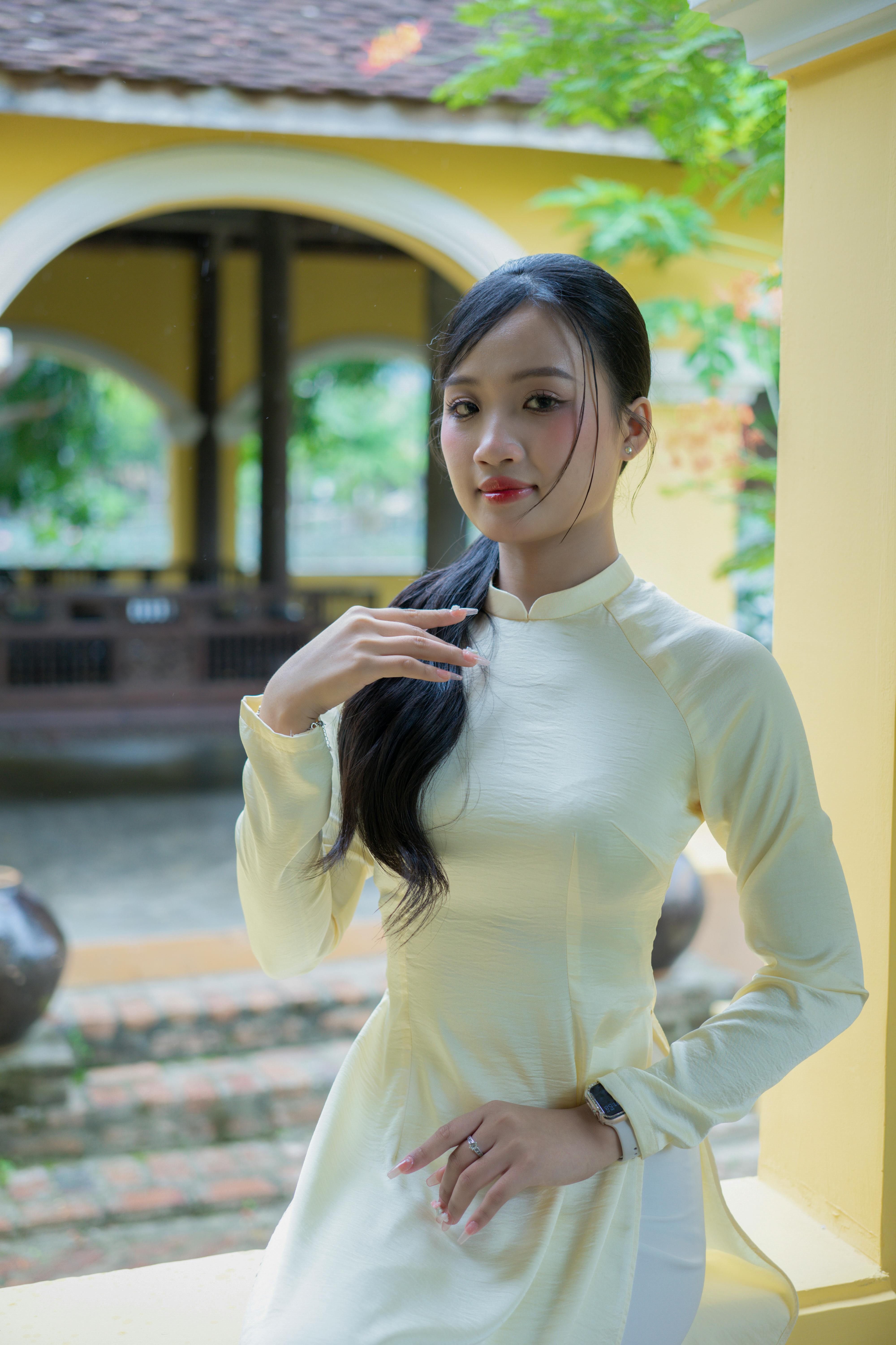 Portrait of an adult woman wearing a traditional Vietnamese Ao Dai in a serene outdoor setting.
