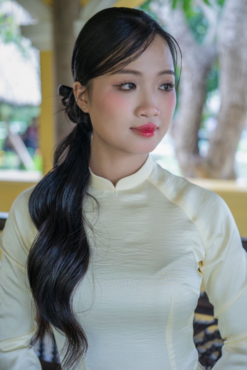 Portrait of a young woman wearing a traditional white Ao Dai, outdoors.