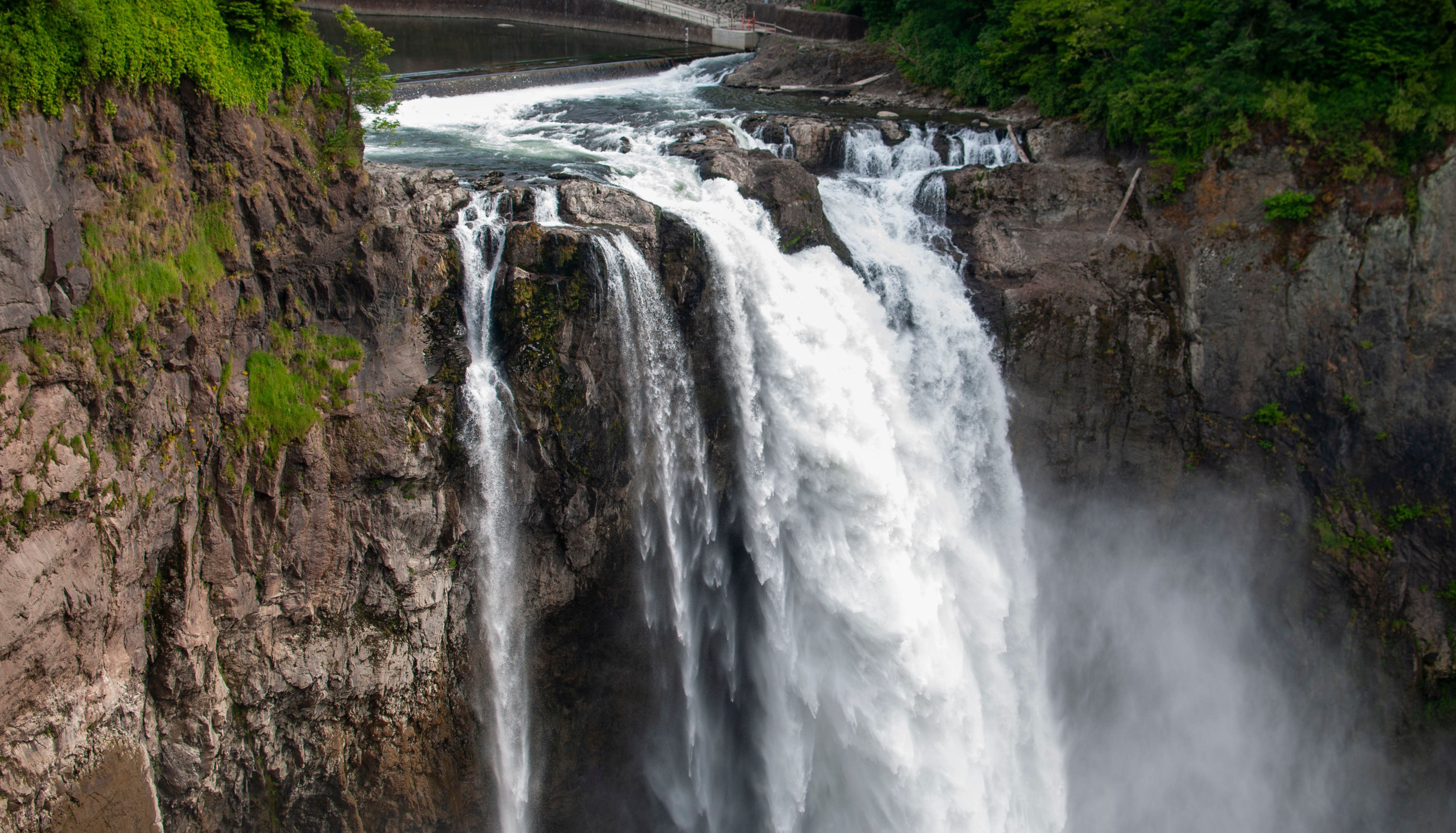 Capture of a majestic waterfall cascading down rocky cliffs surrounded by lush greenery.