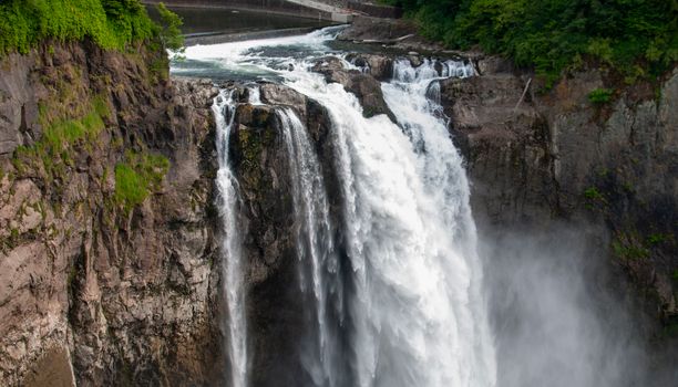 Capture of a majestic waterfall cascading down rocky cliffs surrounded by lush greenery.