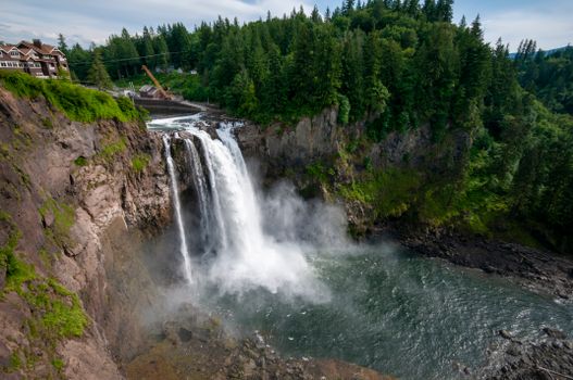 A breathtaking view of Snoqualmie Falls surrounded by lush forest and rugged cliffs.