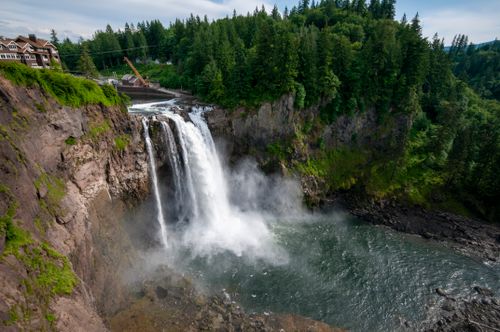 Free A breathtaking view of Snoqualmie Falls surrounded by lush forest and rugged cliffs. Stock Photo
