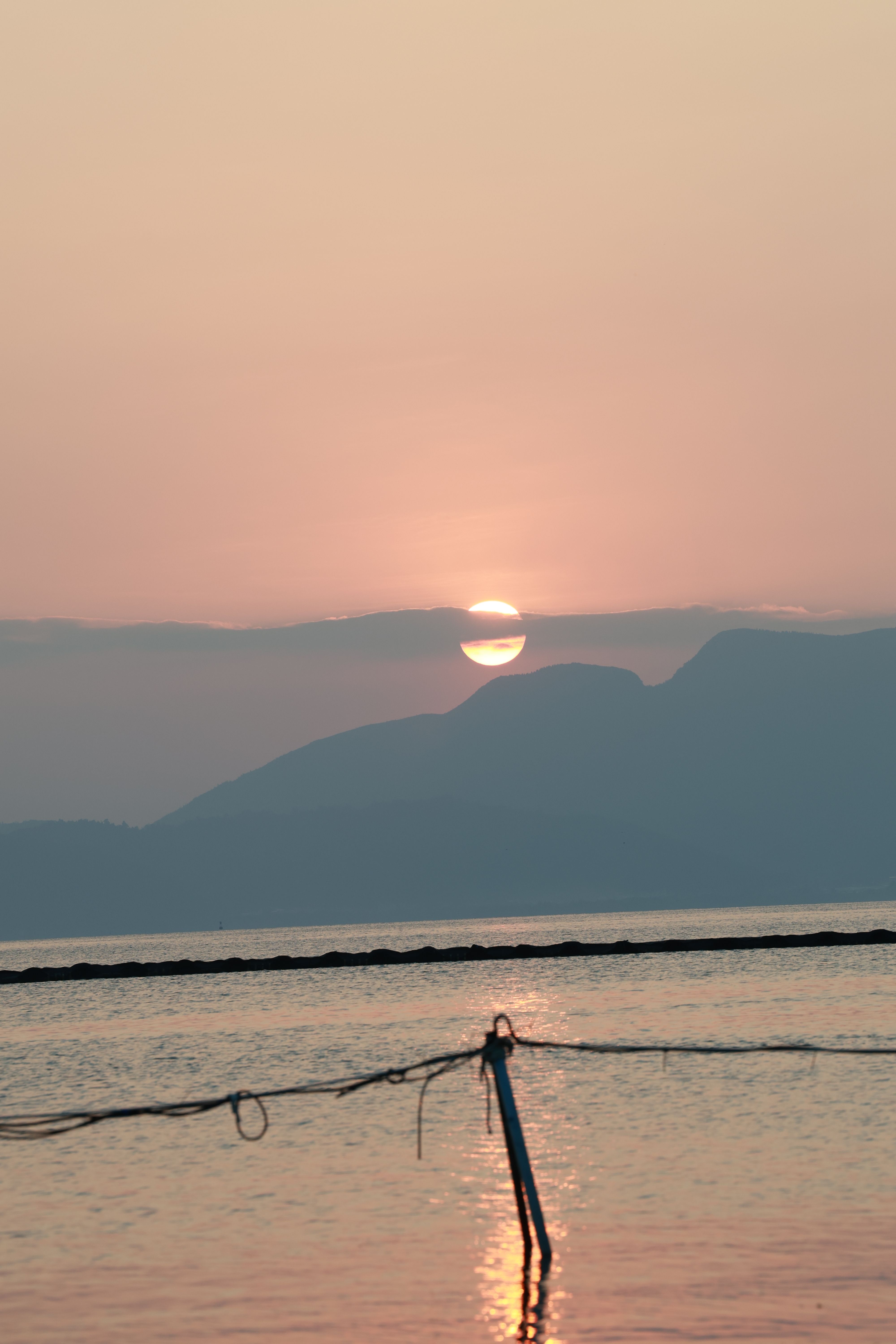 Serene Sunset Over Tranquil Waters and Distant Mountains · Free Stock Photo