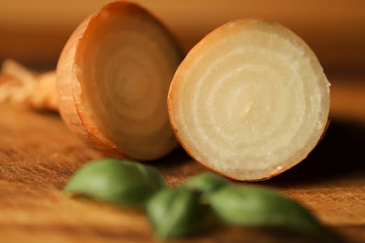 Sliced onion with basil leaves on wooden surface, highlighting freshness.