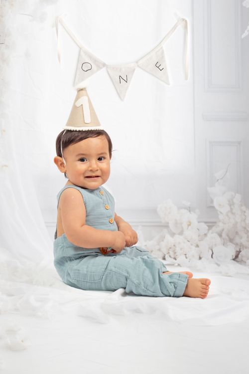 Free Cute baby sitting in a studio with birthday hat and decorations for a first birthday celebration. Stock Photo