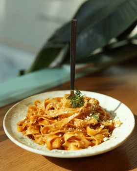 Appetizing tagliatelle pasta dish with parmesan cheese and fresh dill garnish.