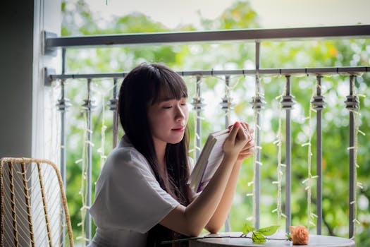 阳光明媚的阳台上绿树环绕，一位年轻女子正静静读书