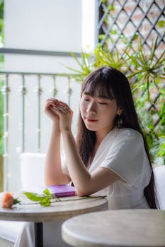 这是一幅宁静的画面：一个女人坐在室内，手捧鲜花和书本，温柔地微笑着