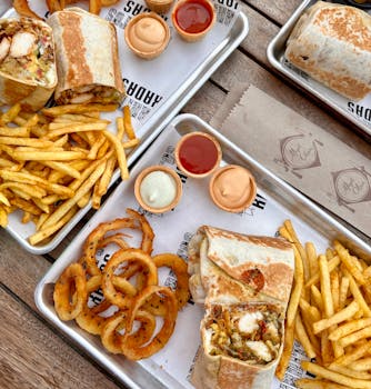 Savor a delicious spread of Mexican wraps, fries, and onion rings with dipping sauces. Perfect for fast food lovers.