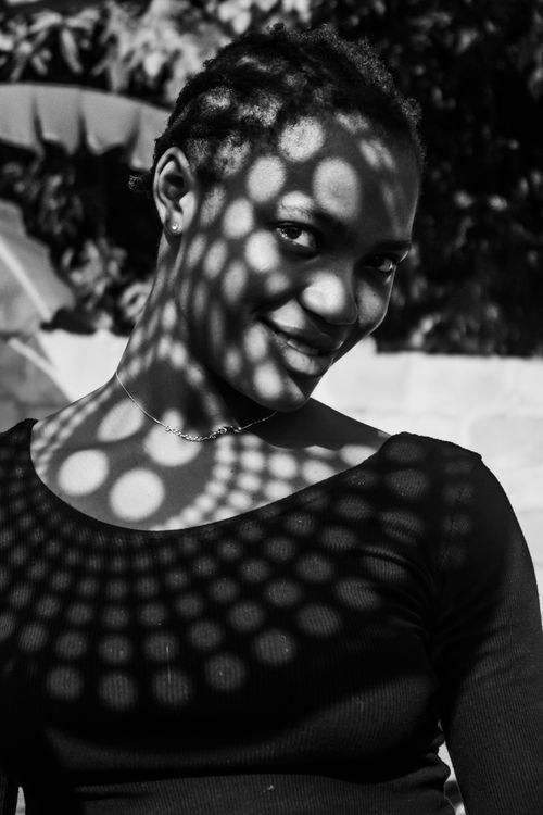 Free A captivating black and white portrait featuring artistic light patterns on a woman's face outdoors. Stock Photo