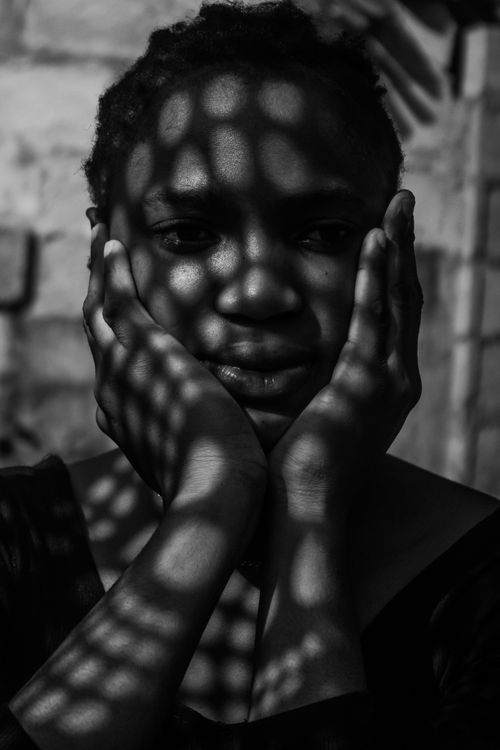 Free Monochrome portrait of a woman with patterned shadows on her face, creating a dramatic effect. Stock Photo