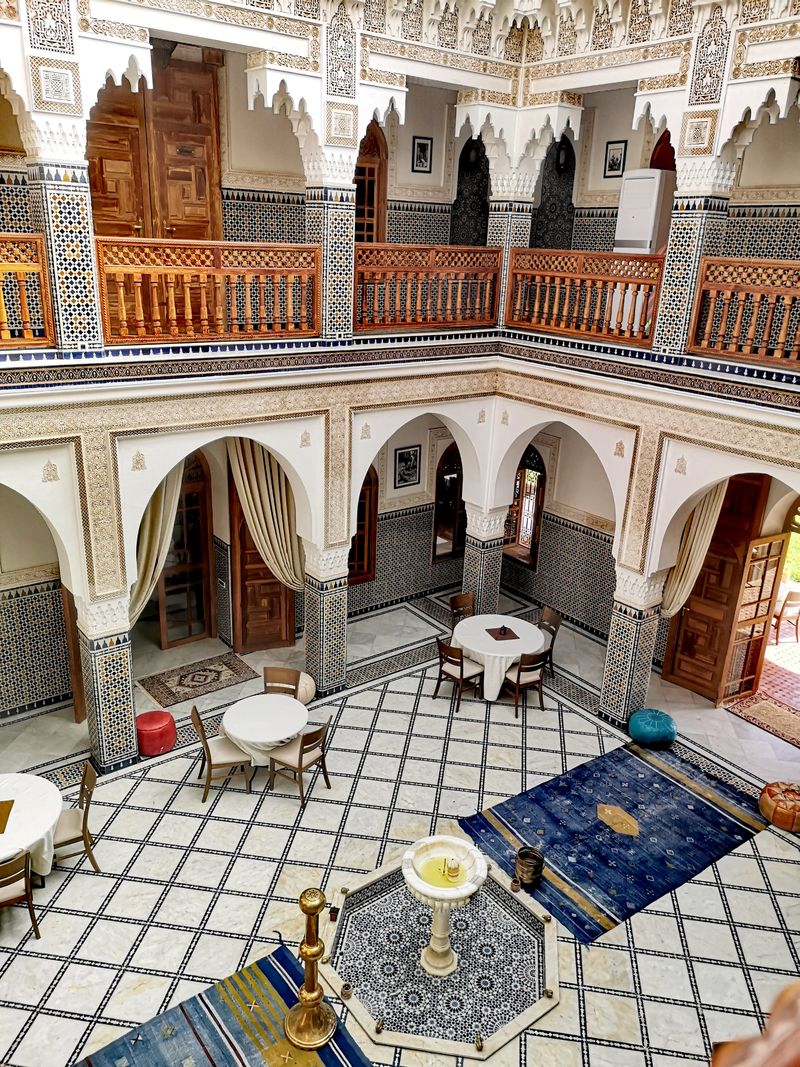 The central courtyard seen from the upper gallery, with a fountain and zellige floor