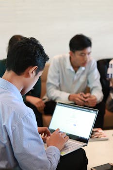 在商务会议上，一群同事使用笔记本电脑进行规划和团队合作