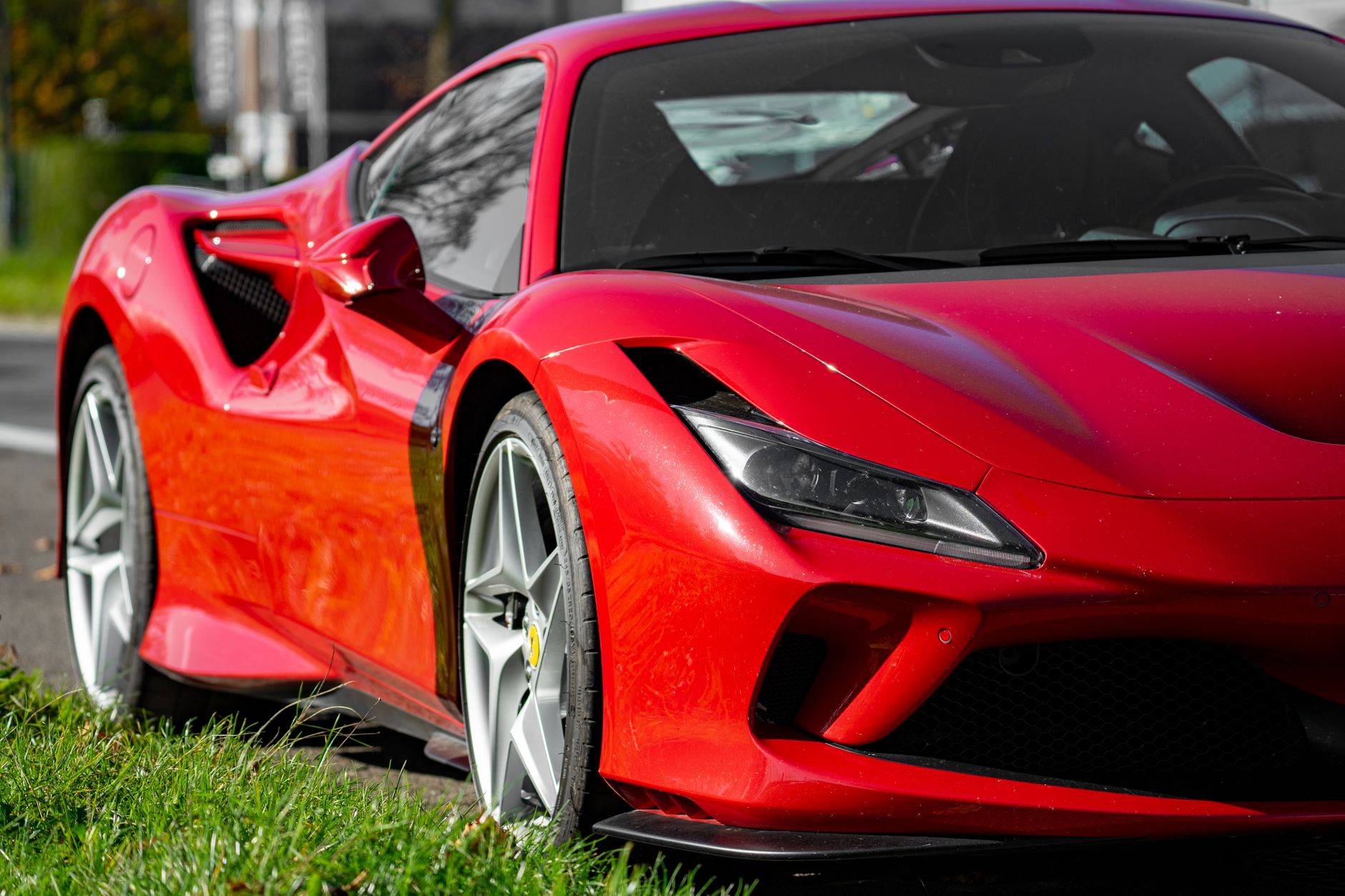A vibrant red sports car parked on the roadside, showcasing sleek design and modern styling. — free online jigsaw puzzle on JigsawPuzzlesFreeOnline.org