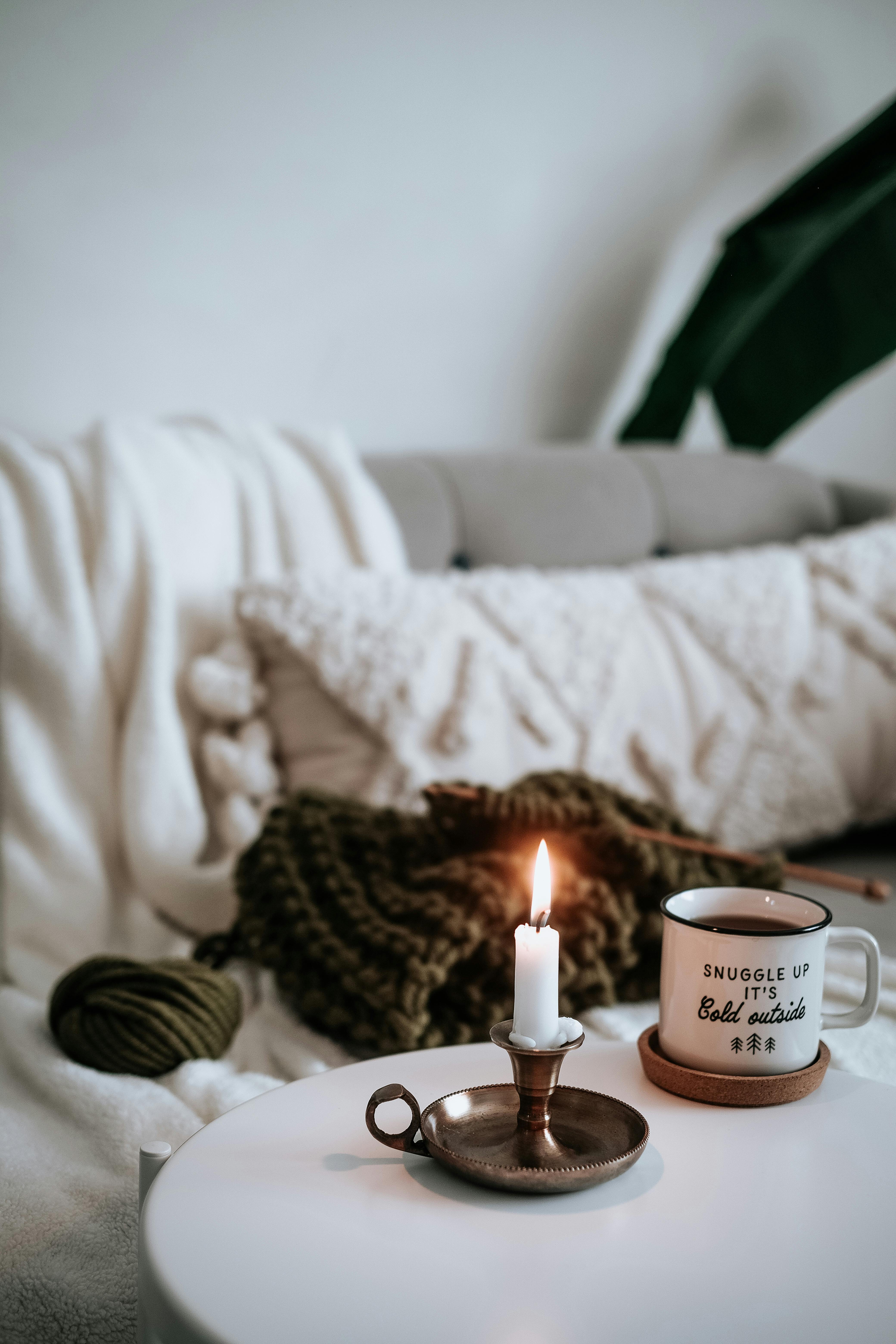 Warm cozy living room scene with a candle and mug, perfect for autumn relaxation.