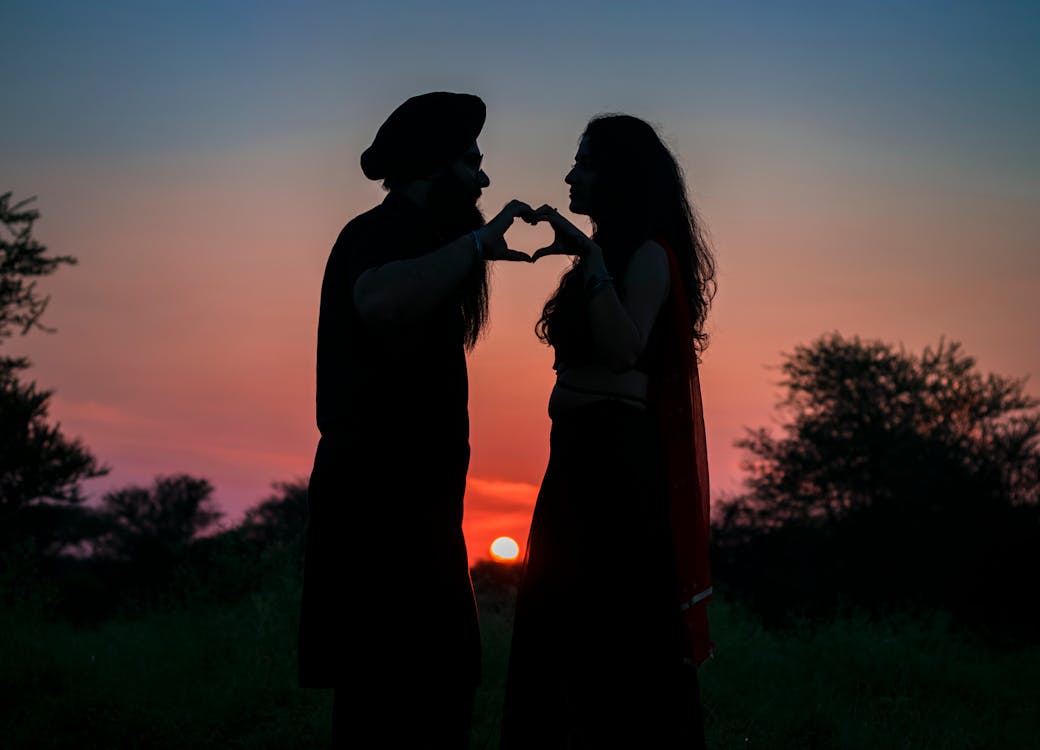 Photo De Silhouette De Couple Faisant Une Forme De Coeur