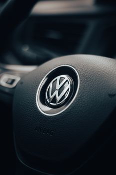 Detail of a Volkswagen steering wheel inside a vehicle's interior. Dark and moody lighting enhances the texture. 29127040