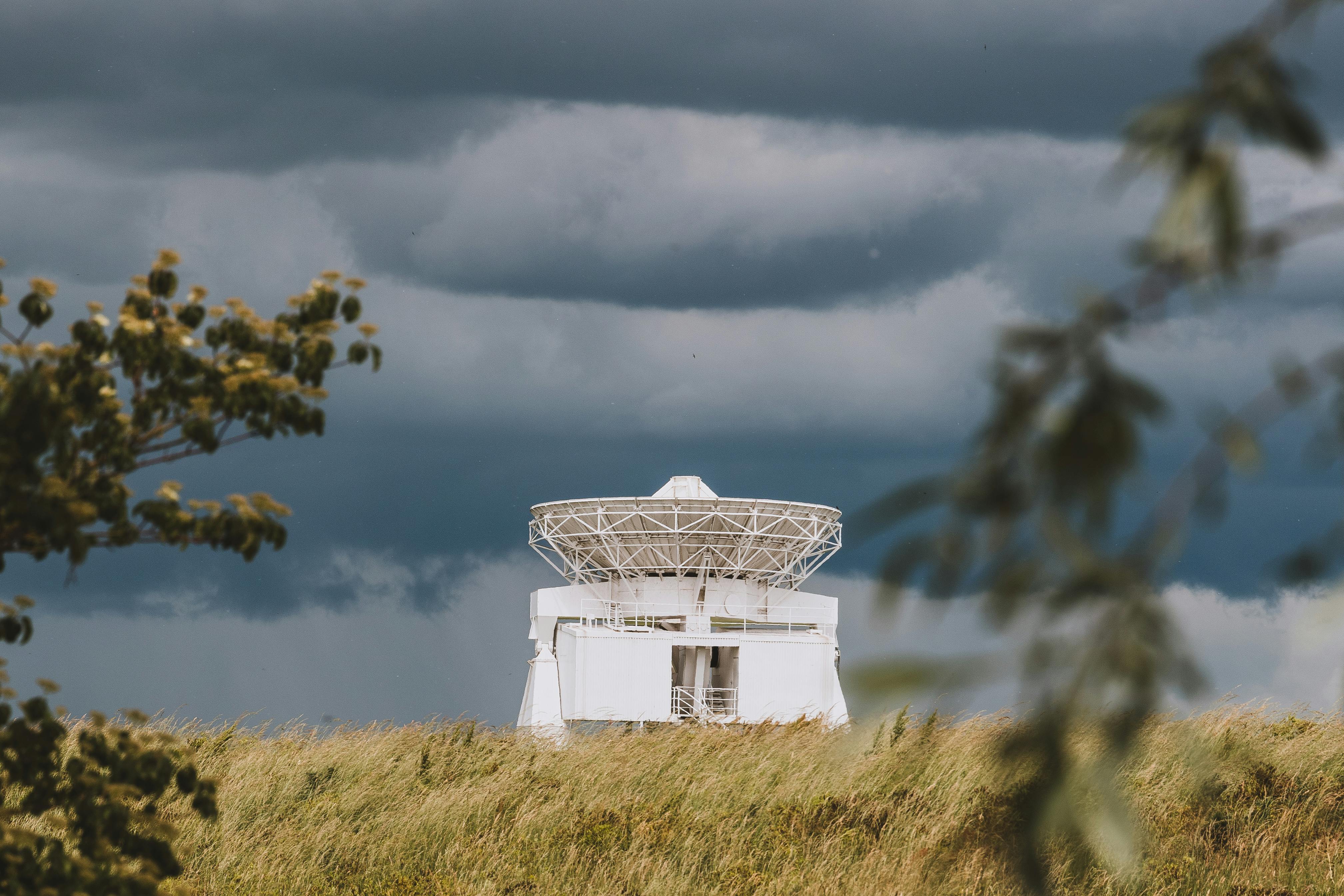 A satellite antenna against a dramatic sky in Riedstadt, Germany, captured from a rural field.