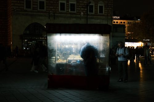 Free Street vendor stall illuminated in the night amidst city crowd. Stock Photo