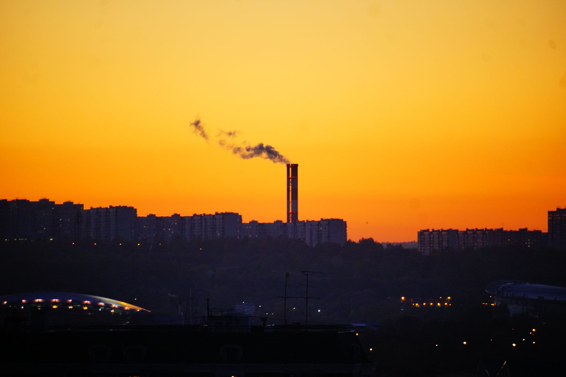 City skyline at sunset with a smokestack, highlighting environmental urban scenes.