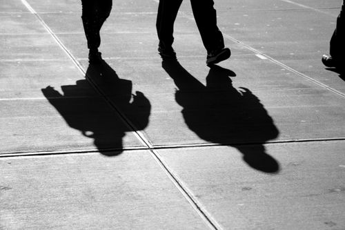 Free Black and white photo of people walking on a sunlit New York City sidewalk, creating vivid shadows. Stock Photo