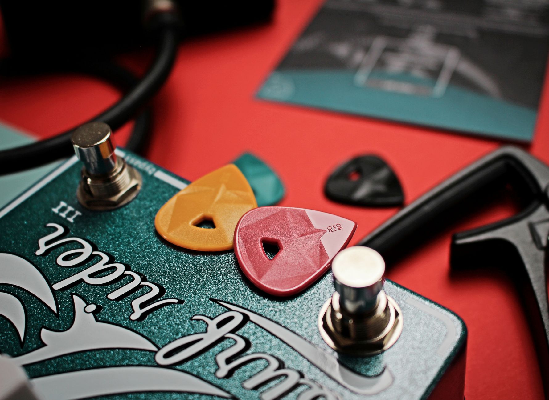 Close-up of colorful guitar picks on an electric effects pedal, showcasing vibrant musical accessories.