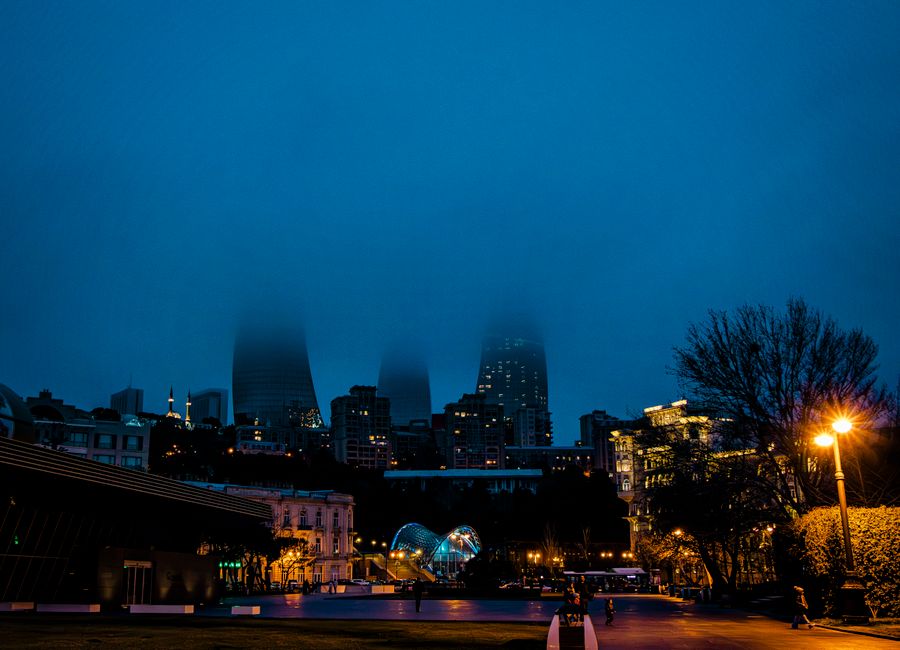 Atmospheric night view of Baku's skyline with mist over modern architecture, Azerbaijan.