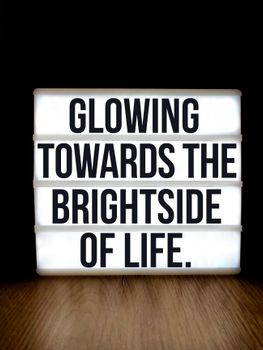 Lightbox sign displaying an inspiring quote on the bright side of life, set against a black background.