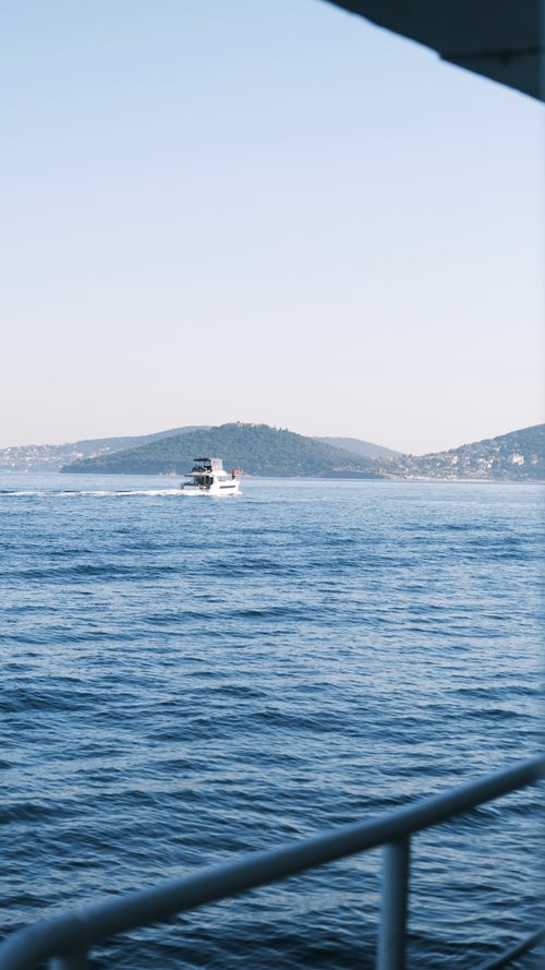 Free A ferry view of a boat cruising on a calm sea against hill backdrop, serene travel scene. Stock Photo