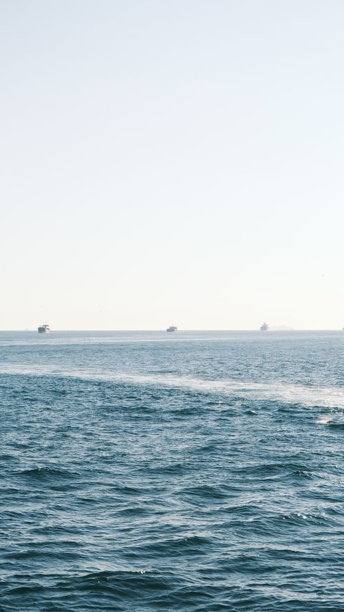 Free Serene ocean scene with distant ships under a clear sky. Stock Photo