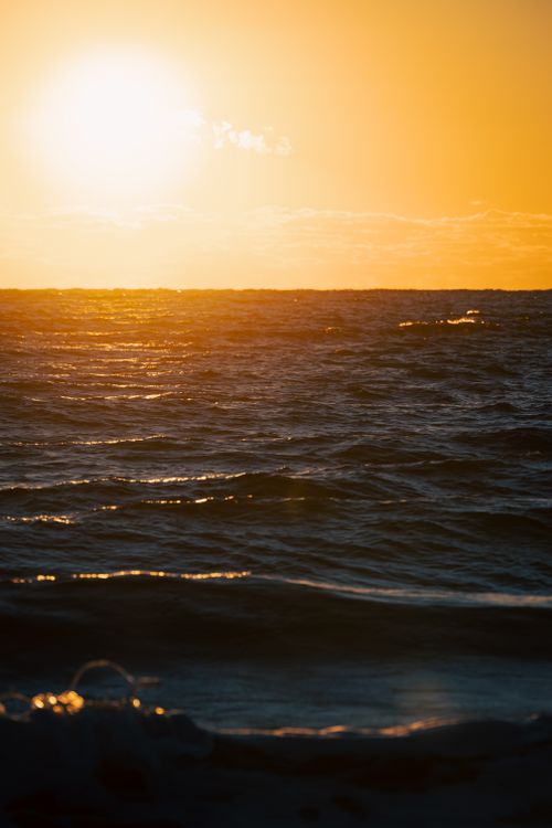 Free Captivating view of a sunset over the ocean with golden hues reflecting on the waves. Stock Photo
