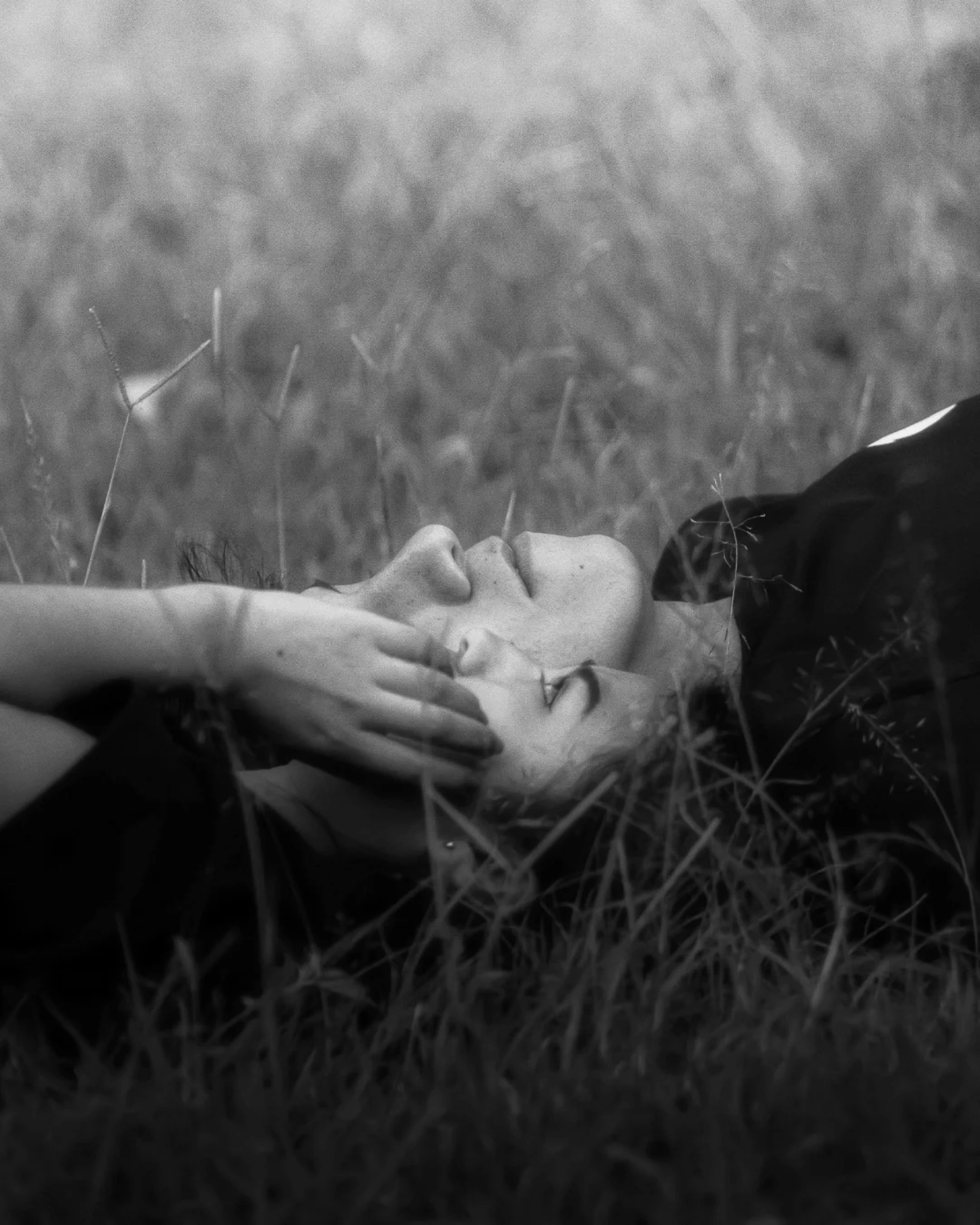 A person lying in grass, enjoying a peaceful moment outdoors.