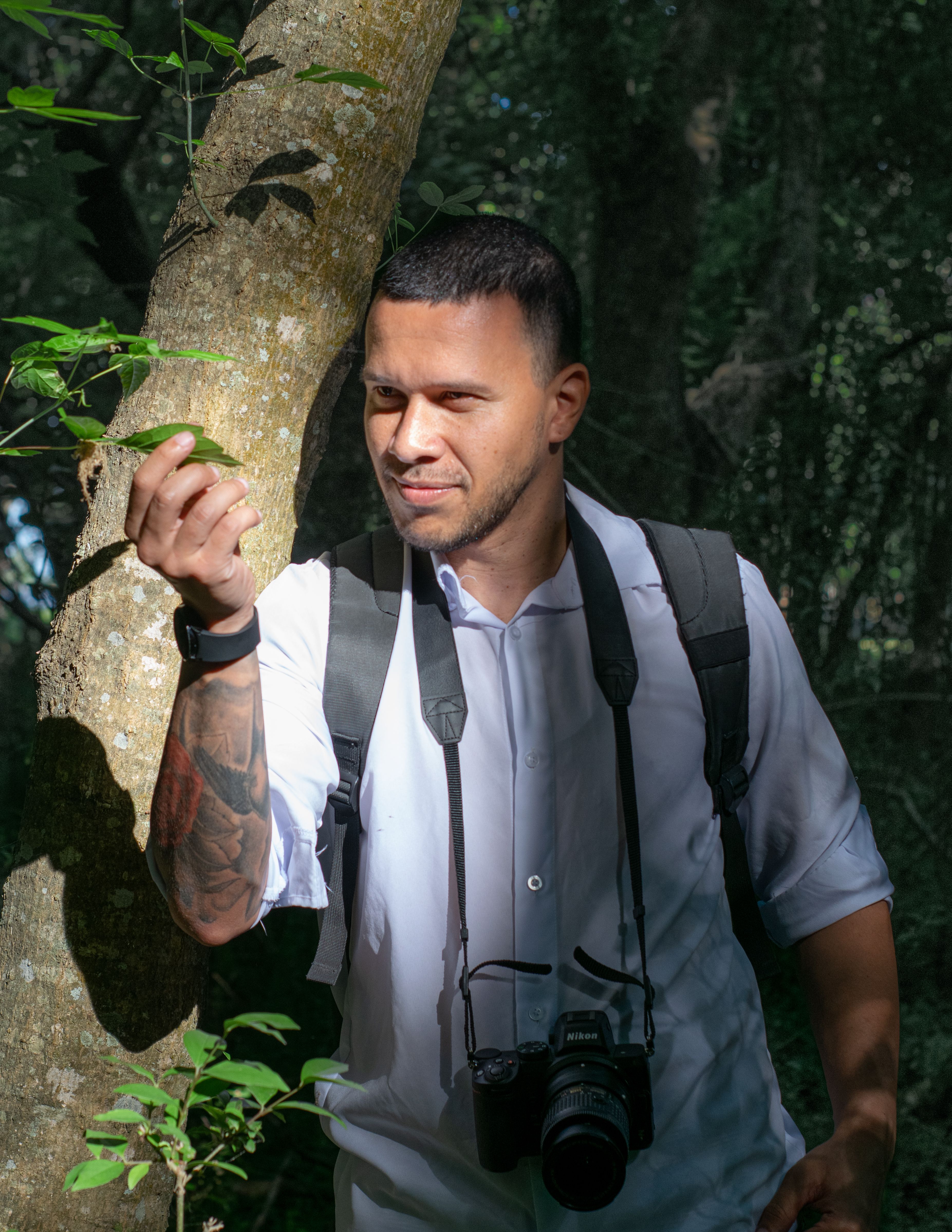 Photographer walking through lush forest in Chascomús, embracing nature with camera.