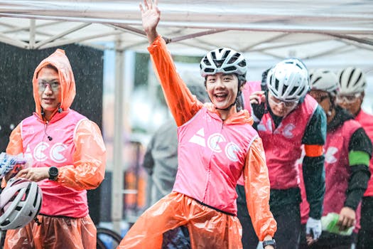 Cyclists in rain gear cheer at an outdoor event, vibrant with excitement and camaraderie.
