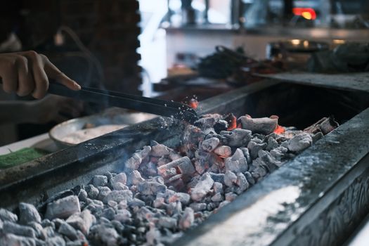 Close-up of grilling meat on glowing embers in a barbecue setup, outdoors in Diyarbakır.
